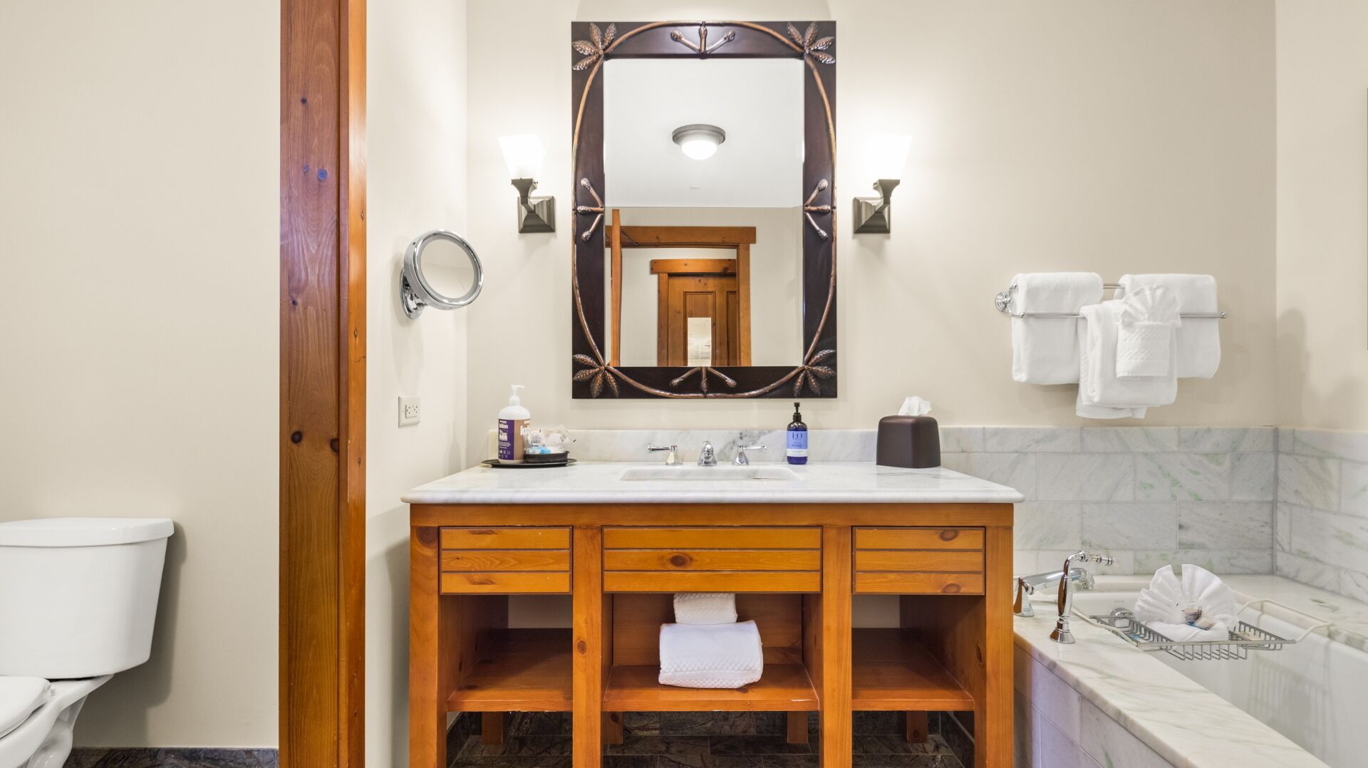 Un baño con tocador de madera, un espejo grande, inodoro y bañera.