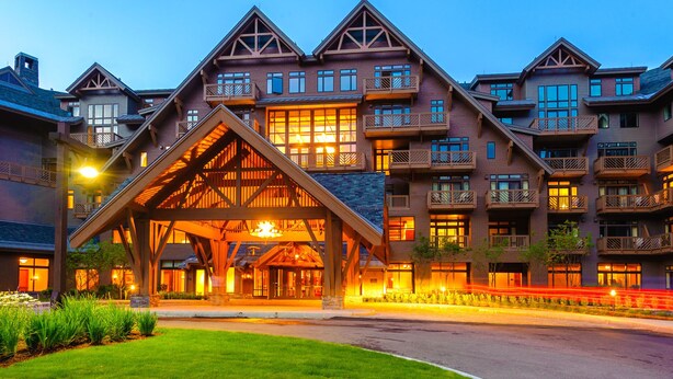 Un hotel de varios pisos con una entrada destacada que presenta un gran arco de madera.