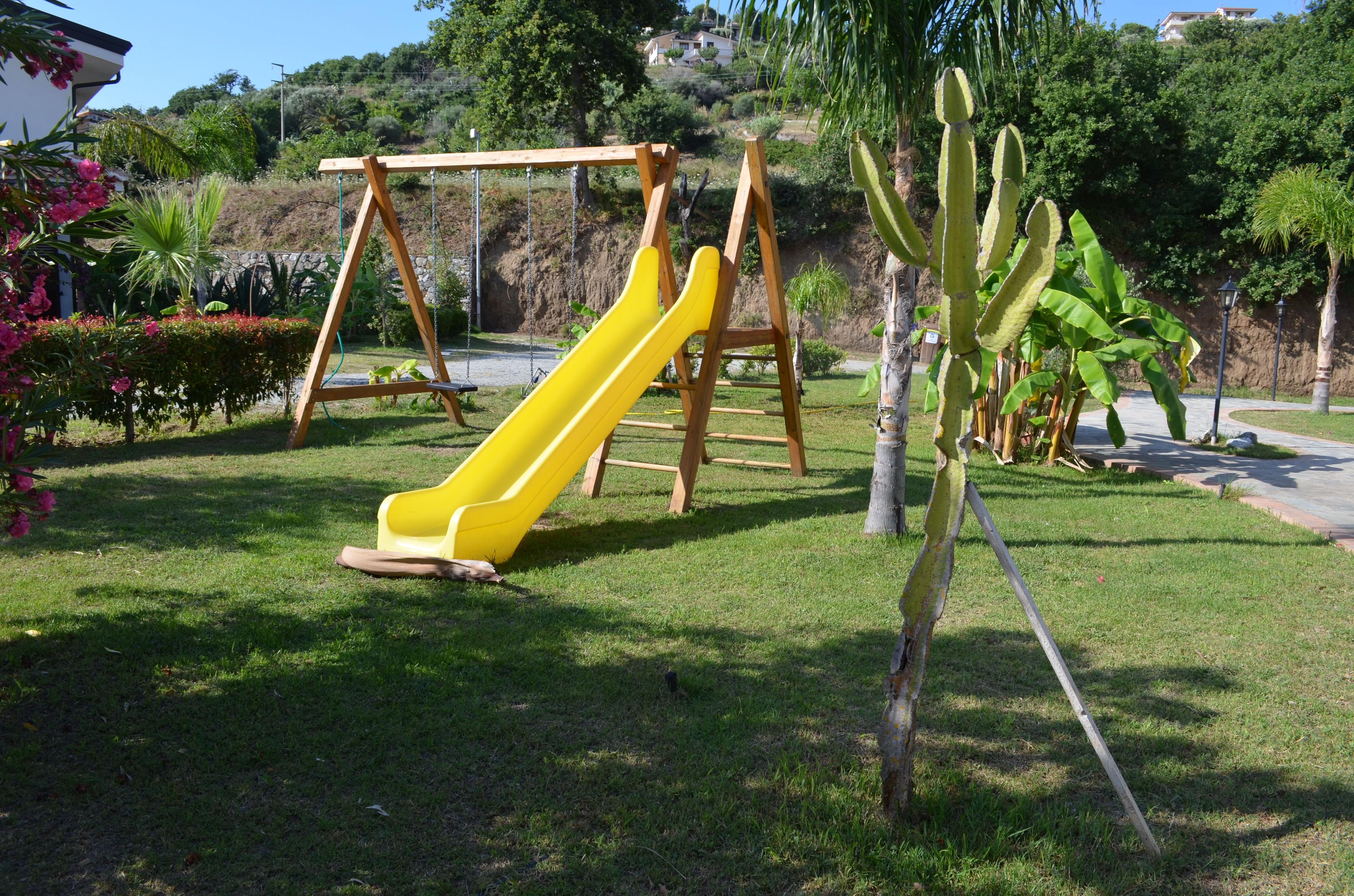 Une aire de jeux avec un toboggan jaune et des balançoires.