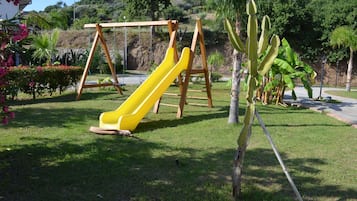 Une aire de jeux avec un toboggan jaune et des balançoires.