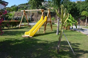A playground with a yellow slide and swings. - Luzia Agriresort (Ricadi)