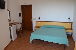 A bedroom with a bed, a desk, a chair, and a small refrigerator. - Luzia Agriresort (Ricadi)
