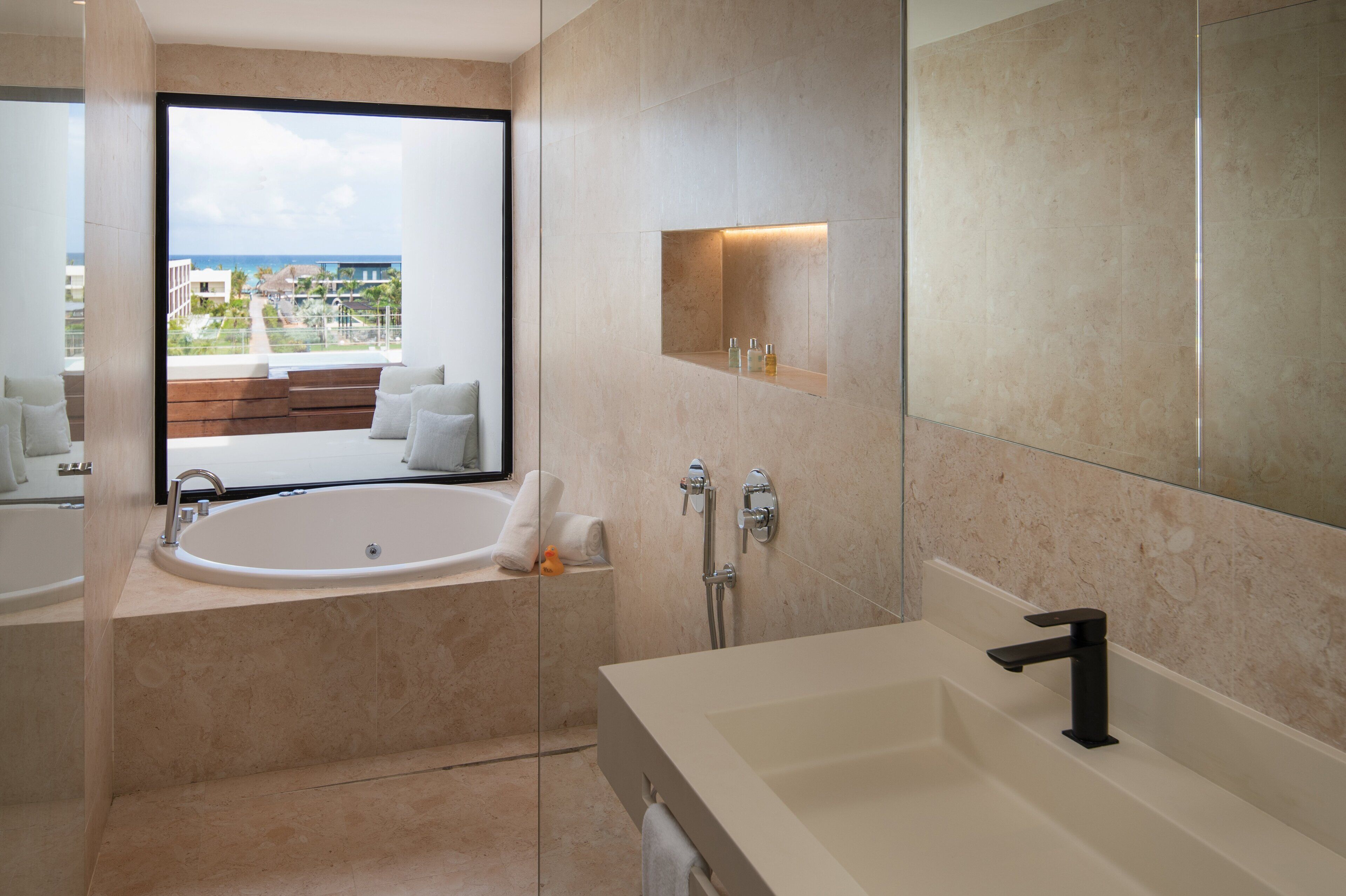 A modern bathroom with a large bathtub, a separate shower area, and a vanity with a mirror.