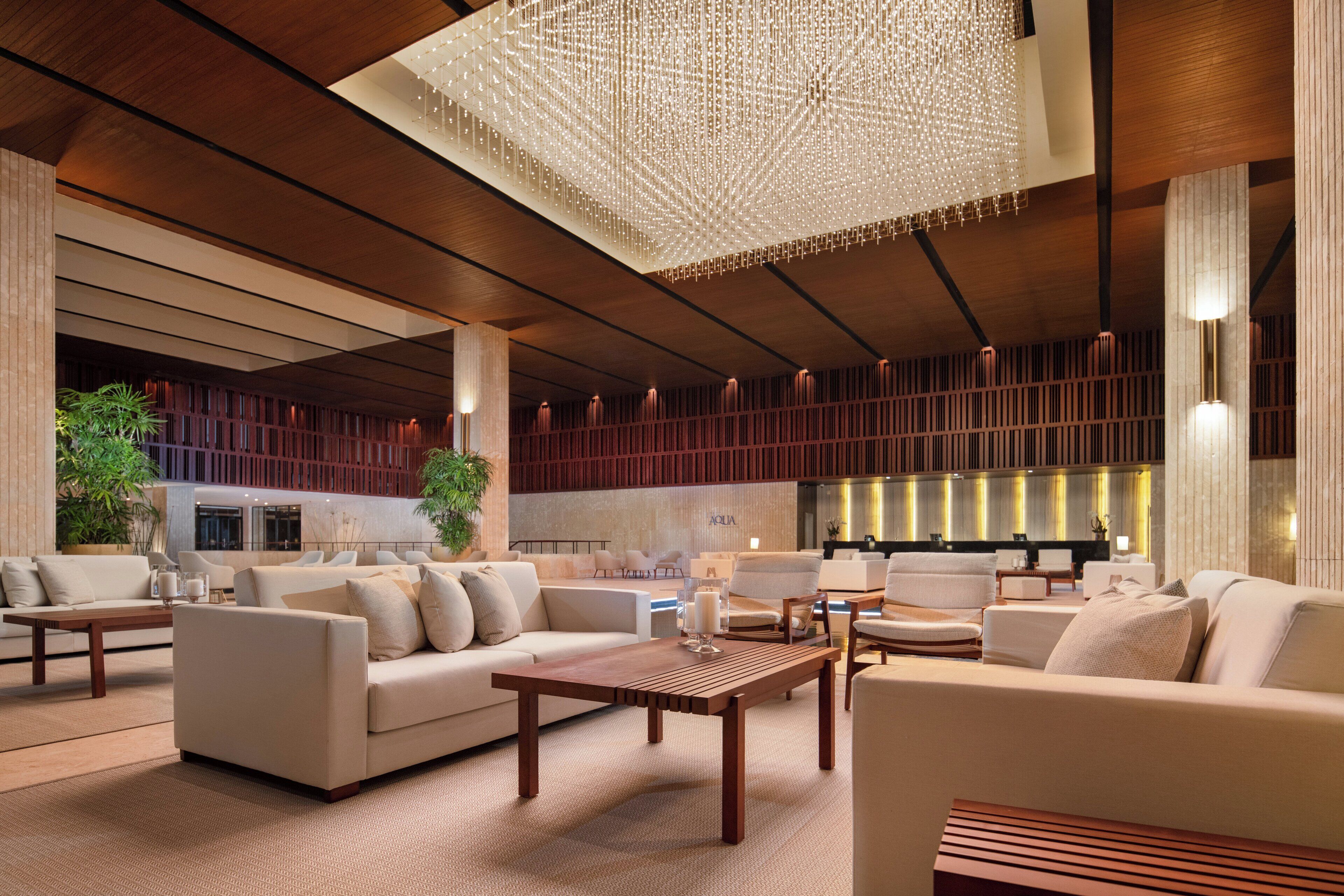A spacious lobby with a high ceiling, modern furniture, and a large chandelier.