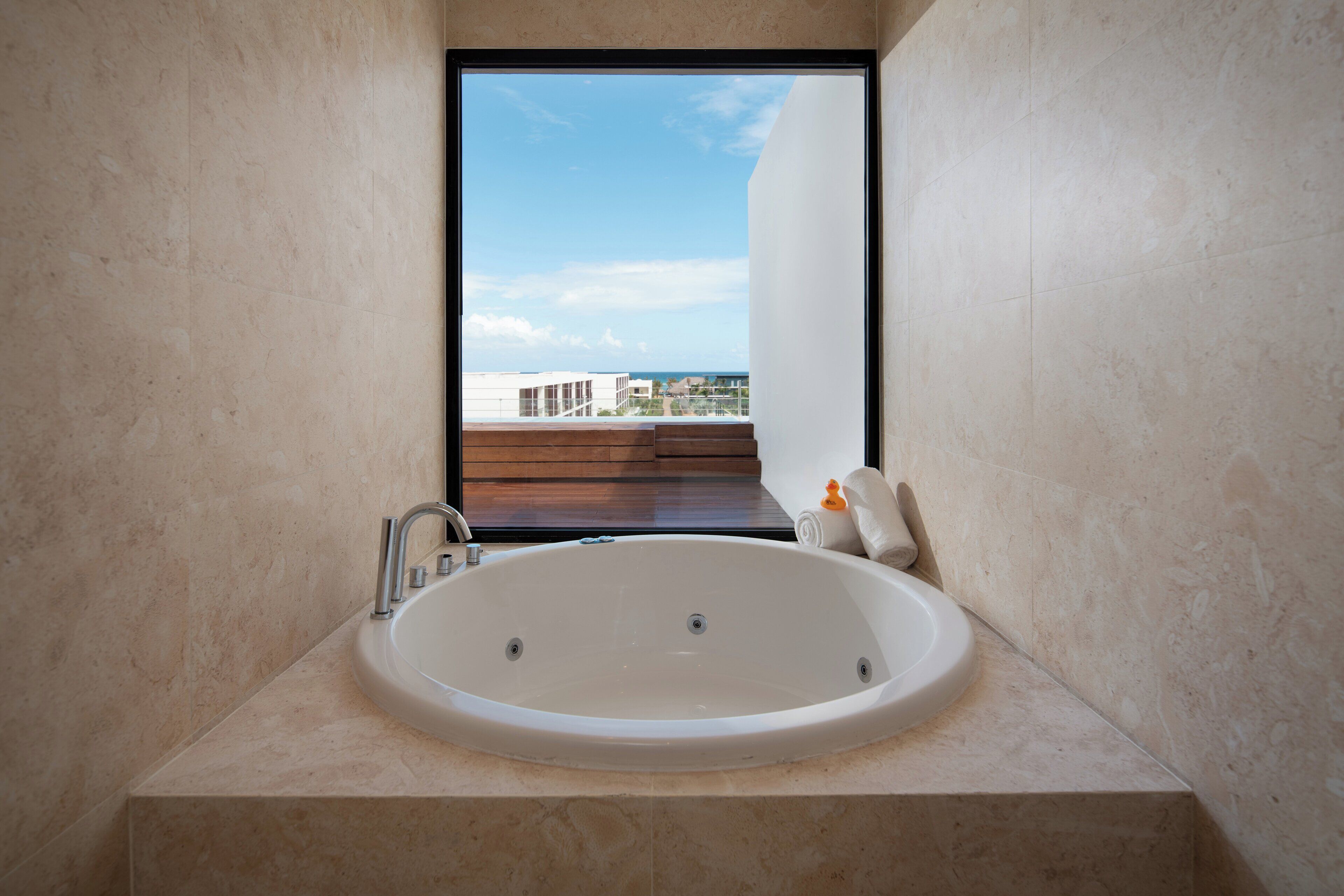 Een moderne badkamer met een groot bad, een raam met uitzicht op gebouwen en een heldere lucht.