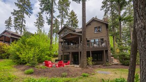 A two-story lodge with a balcony and a deck, surrounded by tall trees and a well-maintained garden. - Golf View, Hot Tub, Suncadia Pool Access (Cle Elum)