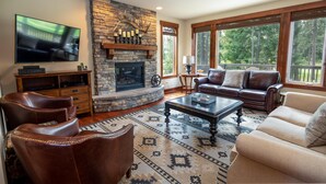 A living room with a stone fireplace, leather furniture, and large windows. - Golf View, Hot Tub, Suncadia Pool Access (Cle Elum)