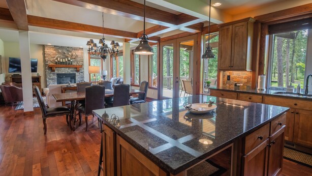 A spacious kitchen with a large island, wooden cabinets, and a stone fireplace. - Golf View, Hot Tub, Suncadia Pool Access (Cle Elum)