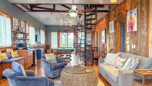 A spacious living area with a pool table, comfortable seating, and a wooden staircase.