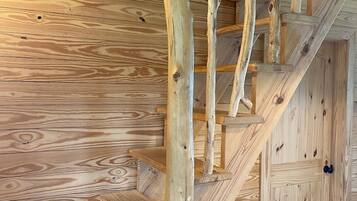 Un escalier en bois, de style rustique, intégré dans une pièce aux murs également en bois.