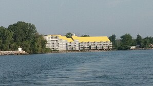 A waterfront hotel with multiple balconies, a yellow roof, and a stone pier. - MBI Sunrise Waterfront Condo - Beautiful Lake Views (Middle Bass)