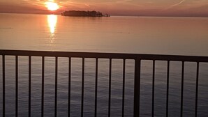 A sunset over a calm body of water with a distant island. - MBI Sunrise Waterfront Condo - Beautiful Lake Views (Middle Bass)