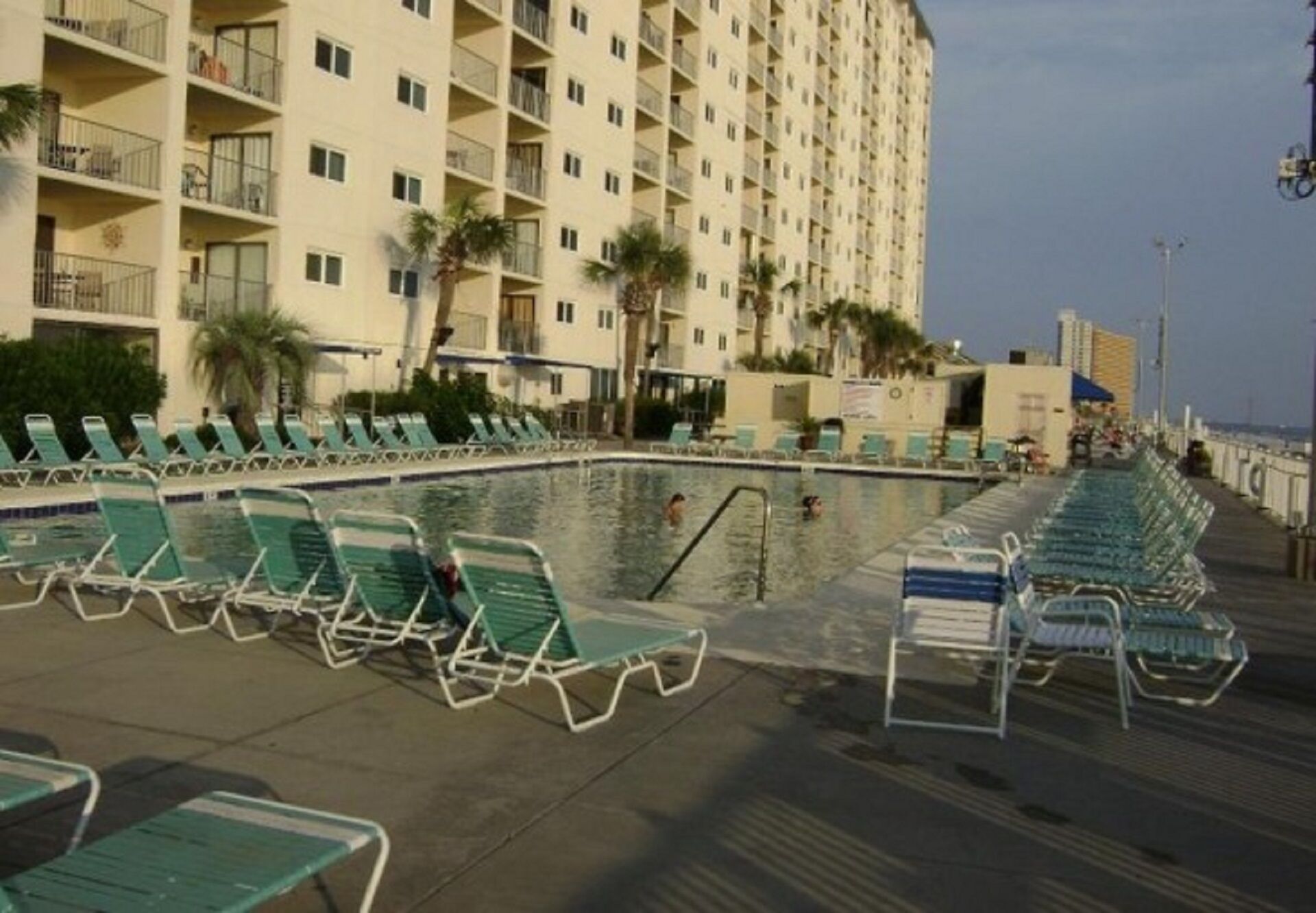 Een hotel met een zwembad en een terras met ligbedden.