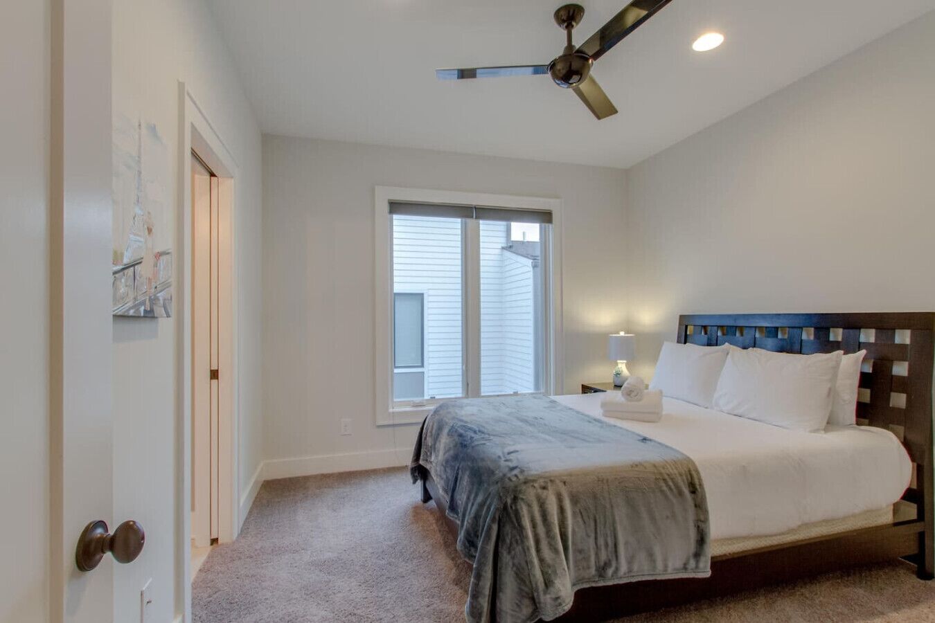 A bedroom with a bed, a ceiling fan, a window, and a door.