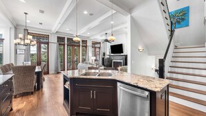 A spacious kitchen with a large island, dark cabinetry, and a stainless steel dishwasher. - Webb Isle Cottage - Close to Shopping, Dining & the Beach! Free Fitness/Tennis (Panama City Beach)