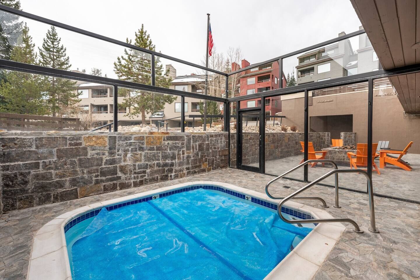 An indoor swimming pool with a stone wall and a view of surrounding buildings.