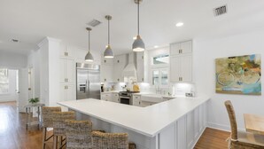 A spacious kitchen with white cabinetry, a large island, and pendant lighting. - Hakuna Matata - 2 Community Pools, Tennis, & Bikes (Santa Rosa Beach)