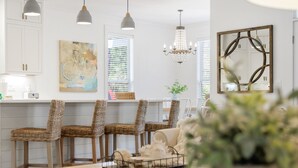 A modern kitchen with white cabinetry, wicker chairs, pendant lights, and a chandelier. - Hakuna Matata - 2 Community Pools, Tennis, & Bikes (Santa Rosa Beach)