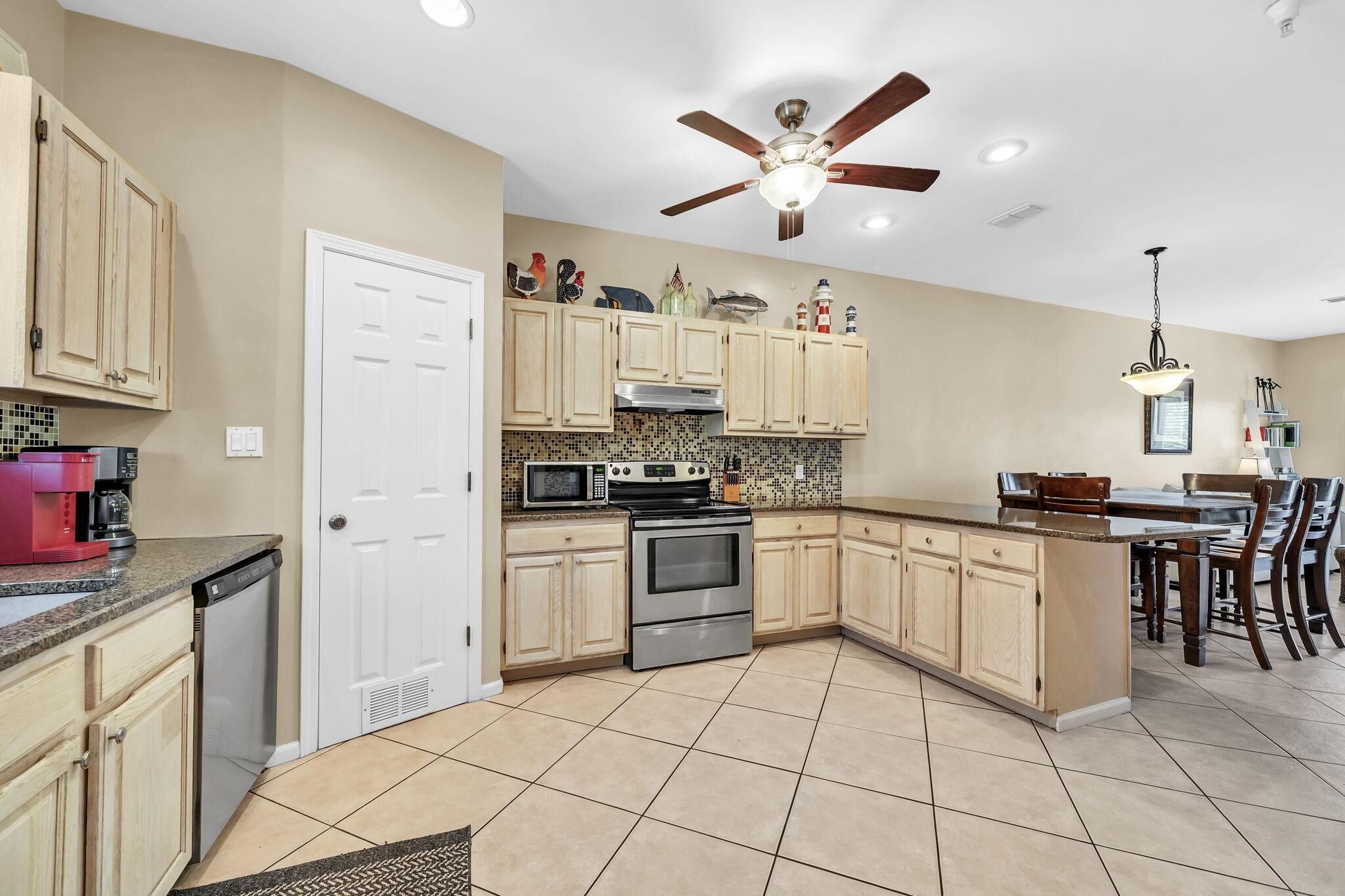 A kitchen with a built-in oven, microwave, and a ceiling fan.