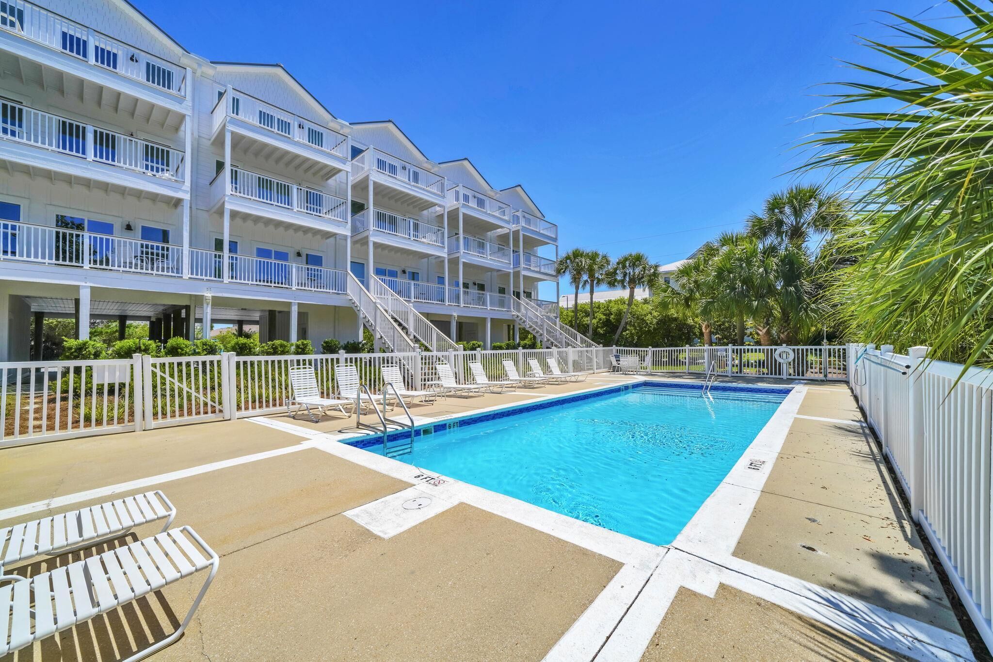 Un hôtel doté d’une piscine, de balcons blancs et de palmiers.