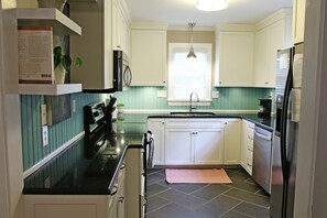 Compact kitchen with a modern design, featuring a black countertop, stainless steel appliances, and white cabinets.