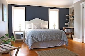 Cozy retreat with a large bed, dark blue accent wall, and a wooden nightstand.