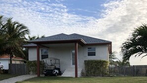 A single-story house with a covered porch, a lawn, and a golf cart parked in front.