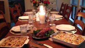 Una mesa de comedor lista para una comida, con varios platos, copas y un candelabro encendido como centro de mesa.