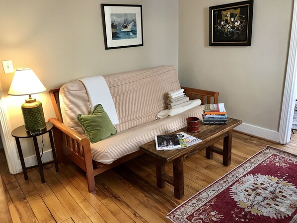 Un salon avec un canapé, une table basse avec des livres, une lampe et un tapis.