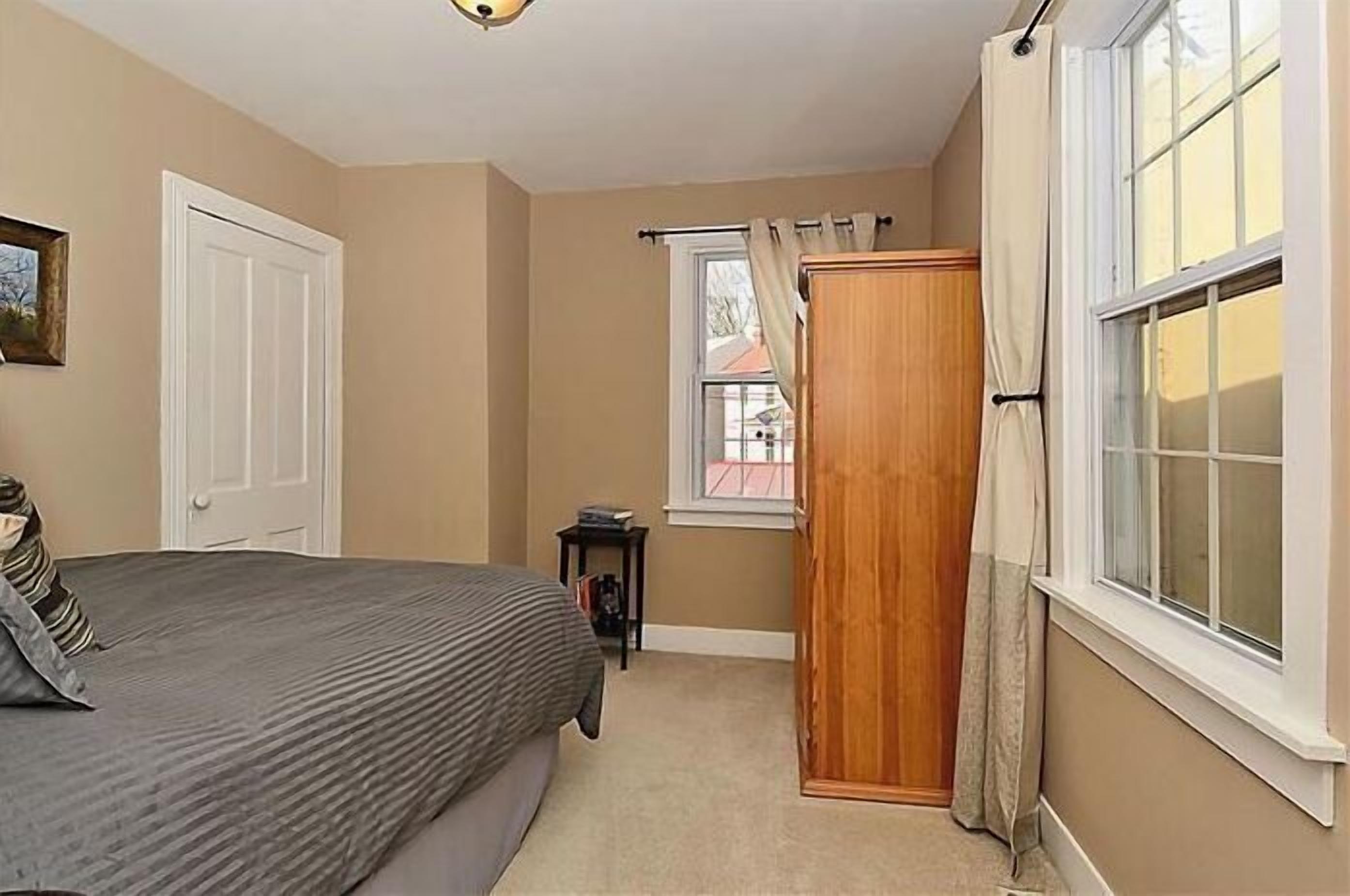 Een slaapkamer met een bed, een kast, een raam en een deur.