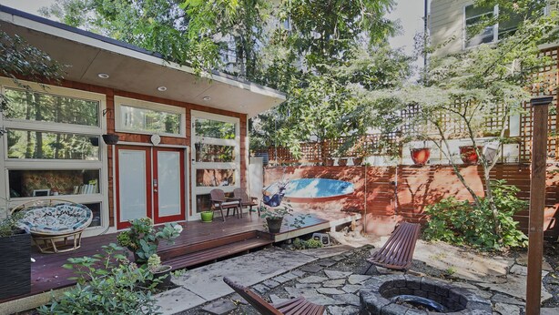 Ein modernes Haus mit Terrasse, Sitzgelegenheiten im Freien und einem Feuerkorb.