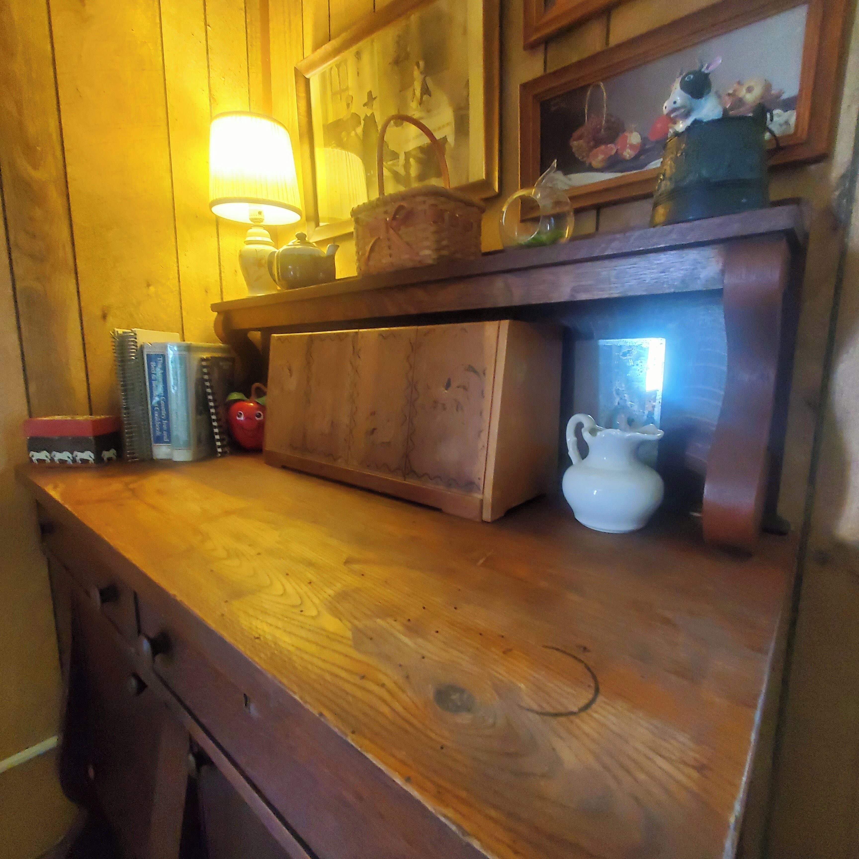 En træbordplade med en lampe, en tekedel og et lille skab.