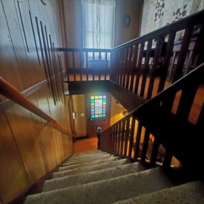 A wooden staircase with a handrail, a window with a stained glass design, and a door with a circular handle. - The Farm House at Peaks of Otter Winery and Orchards (Bedford)