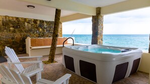 Jacuzzi con pared de piedra y vista al océano.