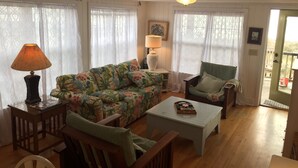 Ein gemütliches Wohnzimmer mit einer blumigen Couch, einem Holztisch und einem grünen Sessel.