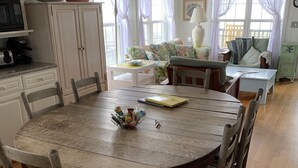 Ein Essbereich mit Holztisch und Stühlen, einer Couch und einer Küche im Hintergrund.