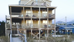 Ein mehrstöckiges Holzgebäude mit Balkonen, einer Treppe und einer Holzterrasse, die zum Eingang führt.