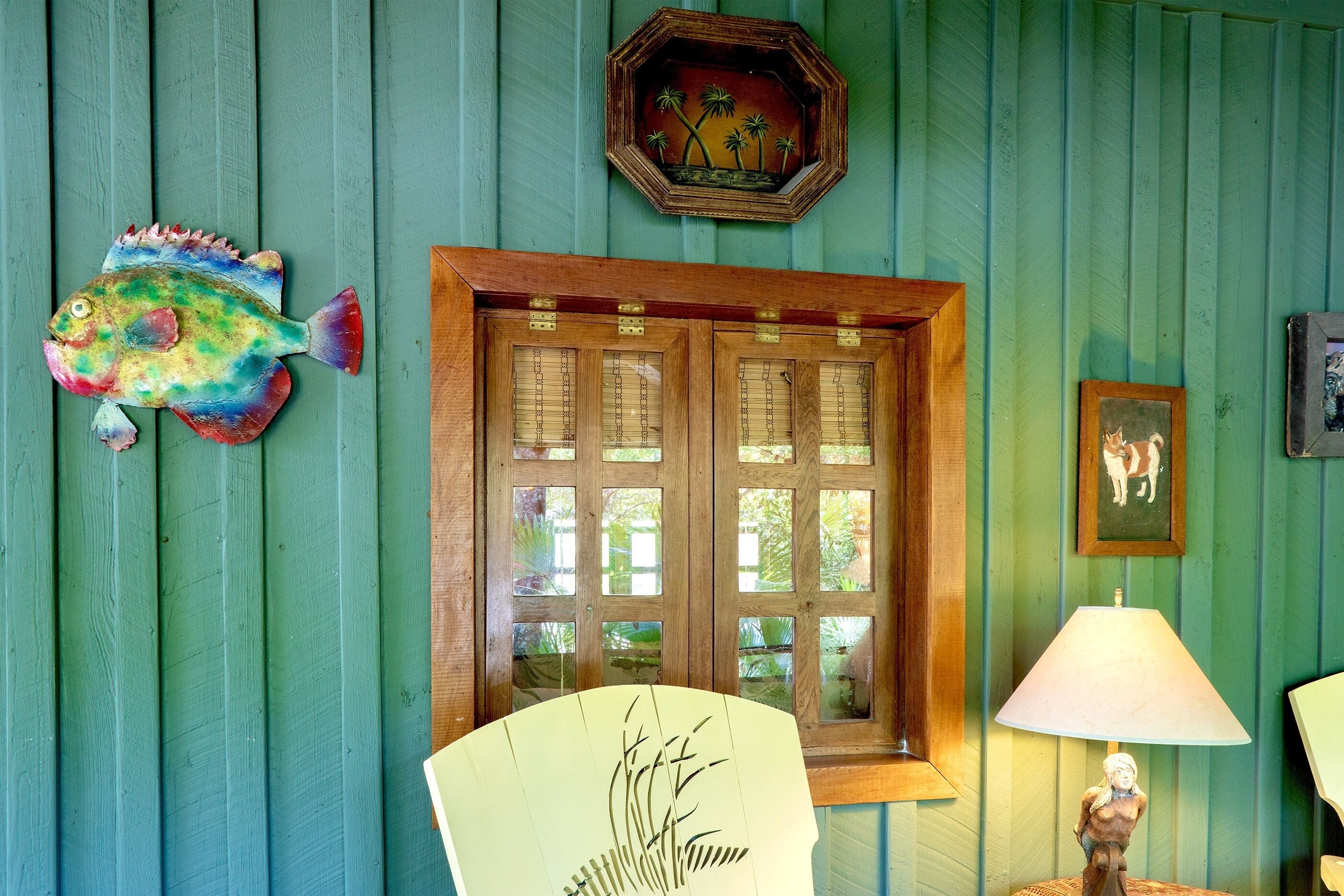 Una habitación con puerta de madera, una decoración de pez, un ventilador y una lámpara.