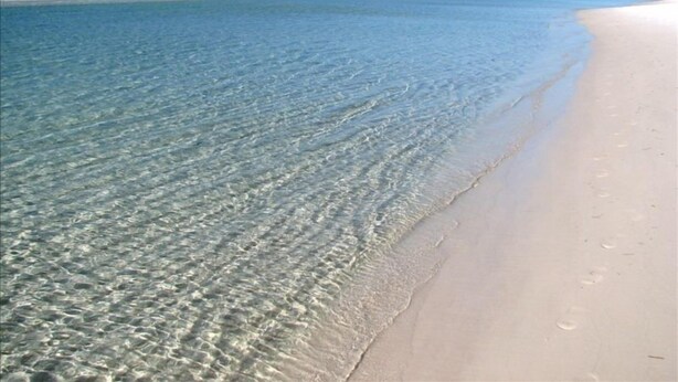 Een strand met helder ondiep water en een zandstrand.
