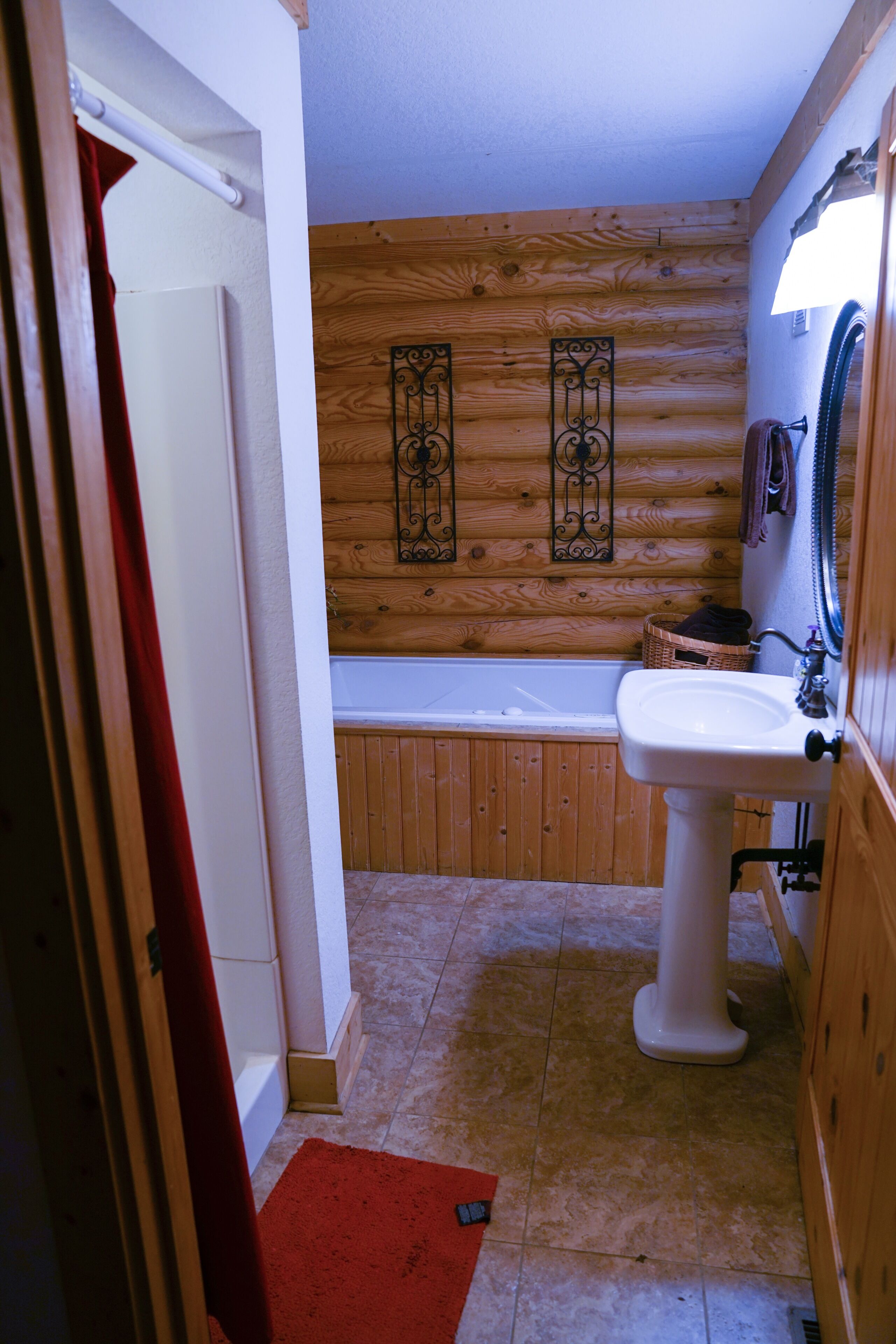 A bathroom with a wooden wall, a white sink, and a bathtub.