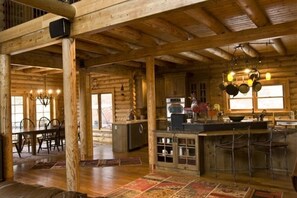 Cozy cabin interior with a dining area, kitchen, and fireplace, perfect for communal meals and relaxation.