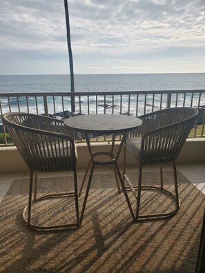 Un balcon avec vue sur l’océan, comprenant deux fauteuils en osier et une petite table ronde.