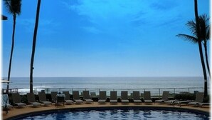 Ein Poolbereich mit Liegestühlen und Blick auf den Ozean.