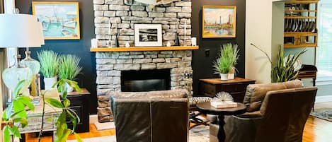 Un salon moderne avec une cheminée en pierre, des canapés en cuir et un plancher en bois.