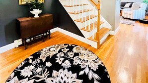 A spacious living room with a wooden staircase, a large mirror, and a patterned rug. - NEWLY RENOVATED! 5-Star, Edgartown Colonial with Central AC (Edgartown)
