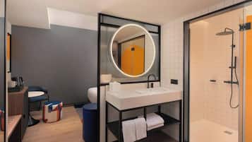 Un baño moderno con un espejo redondo, lavamanos blanco y zona de ducha.