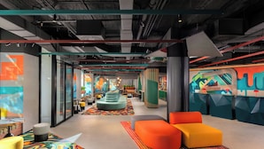 Een modern interieur met een centrale zithoek, glazen wanden en kleurrijke kunstwerken.