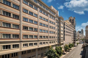 A multi-story hotel with a modern architectural design, featuring a prominent entrance and a clear view of the street. - Aloft by Marriott Madrid Gran Via (Madrid)