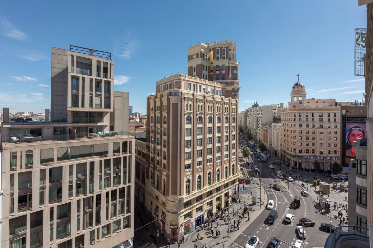 Un edificio de varios pisos con una mezcla de arquitectura moderna y clásica, que destaca una torre en esquina y una estructura en forma de cúpula.