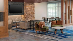 A modern lounge area with a stone wall, a flat-screen TV, and a mix of seating options including sofas and chairs.